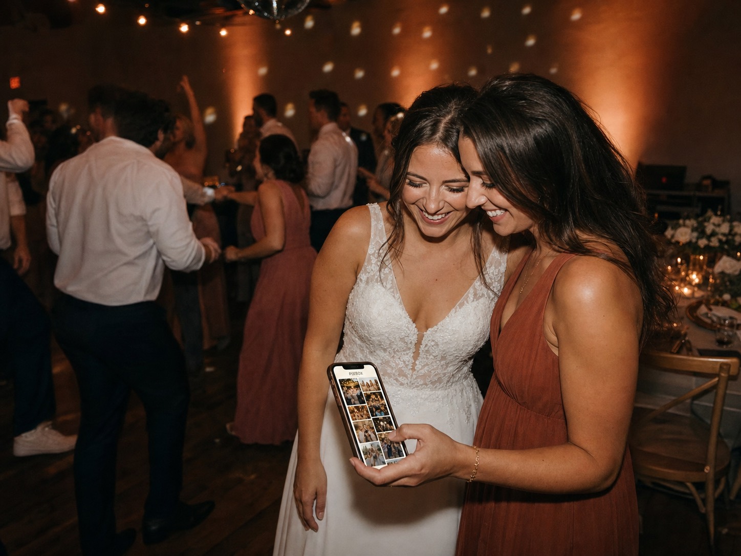 Bride and friend enjoying their collected The Wedding Pics wedding gallery beside the dance floor